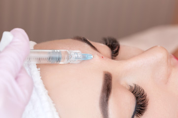 Cosmetologist does prp therapy anti wrinkle and aging skin on the face of a beautiful woman in a beauty salon. Cosmetology concept.