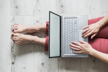 Top view of a faceless woman working from home. A girl sits on the floor in her apartment and works...