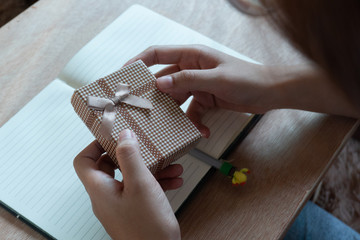 Close up shot of female hands holding a small gift . Small gift in the hands of a woman indoor.