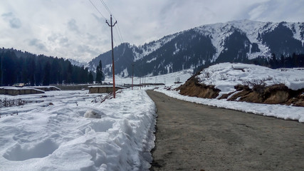 An abandoned road all covered in snow with Himalayas mounains in the backdrop. Winter drive to...