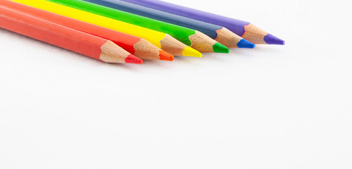 Color pencils on white background with copy space. Row of color pencils arranged in rainbow color on white background.