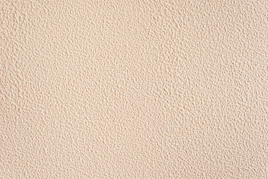 Textured nude background. Decorative plastering, external decoration of the facade. Background image of a wall with beige rough coating.