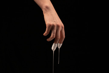 Female hand in liquid white, drops drip from fingers, on a black background. Human hands isolated in a black background.