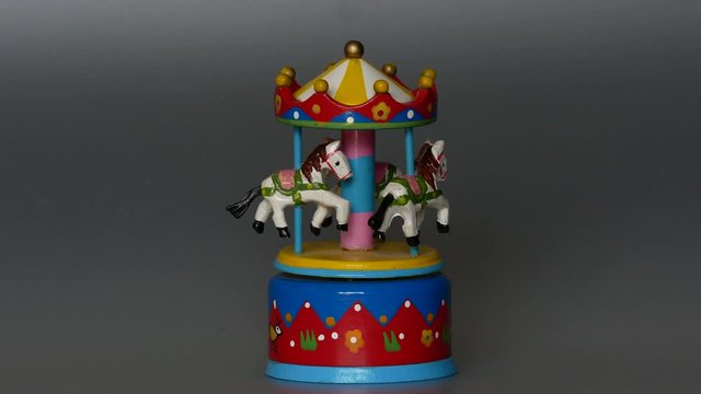  Toy rotating carousel with three white horses horse  music box, dark gray  background
