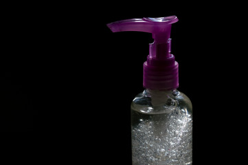 plastic dispenser pot with alcohol gel, beautiful bubbles inside, isolated on black background and dramatic lighting - health, virus and bacteria control concept