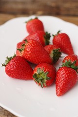 Juicy strawberries in a white plate on the table 