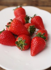 Juicy strawberries in a white plate on the table 
