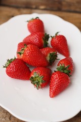 Juicy strawberries in a white plate on the table 
