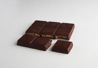 broken bar of dark chocolate on a white background