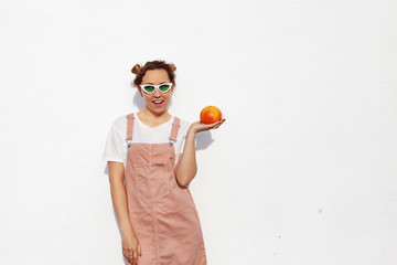 Studio portrait of happy girl, smiling cheerfully, holding ripe grapefruit in hands, standing isolated over white background. Tasty tropical fruit, healthy food, raw food diet