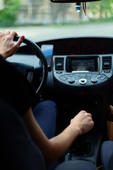 Man driving. The driver holds the steering wheel with his hand. And shifts the speed on the manual transmission