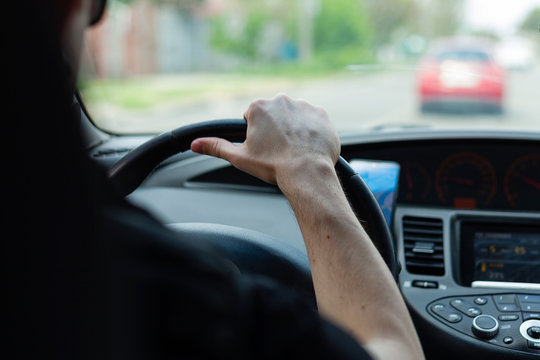 Man driving. The driver holds the steering wheel with his hand.