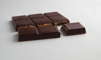 broken bar of dark chocolate on a white background