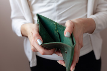 A girl in a protective mask holds a purse. Green purse in women's hands. The concept of poverty and...