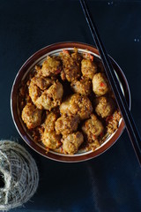very spicy meatball in a bowl with chopsticks for snacks or lunch in dark background