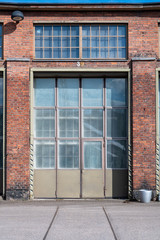 An old red brick rail yard complex with vintage glass window frames and large industrial doors.
