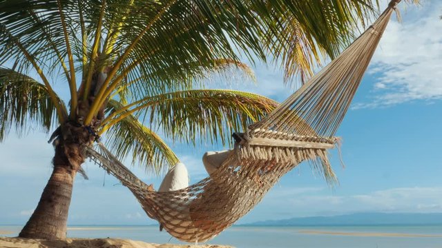 Relaxed woman swinging in a hammock at sand beach of Thailand
