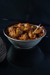 very spicy meatball in a bowl with chopsticks for snacks or lunch in dark background
