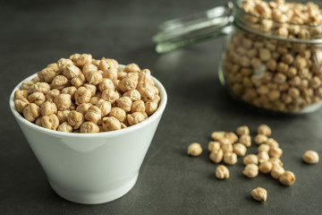 Raw chickpea in white porcelain bowl on stone, concrete background. Healthy and organic cereal.