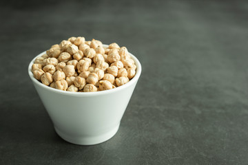Raw chickpea in white porcelain bowl on stone, concrete background. Healthy and organic cereal.