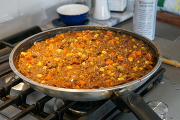 Cooking stew with meat, carrots, corn and potatoes in frying pan