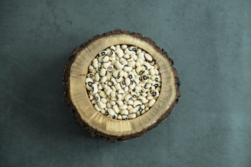 White kidney bean in wooden bowl on concrete, stone background. Healthy, organic and delicious cereal. Top view, flat lay.