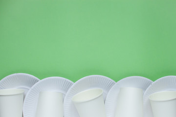 The layout on a green background from paper disposable plates. Caring for the environment. Recycling and sorting of garbage. Disposable tableware. Environmental pollution....