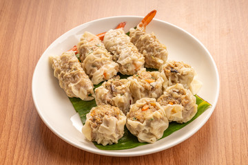 White Dish of Asian Steam  Dumplings  or Dim Sum a Famous Chinese Food  with Pork and Shrimp on  Wood Table.