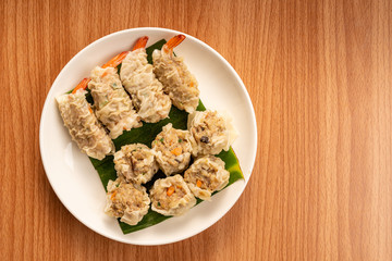 White Dish of Asian Steam  Dumplings  or Dim Sum a Famous Chinese Food  with Pork and Shrimp on  Wood Table.