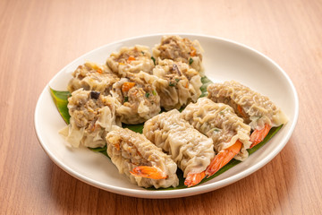 White Dish of Asian Steam  Dumplings  or Dim Sum a Famous Chinese Food  with Pork and Shrimp on  Wood Table.