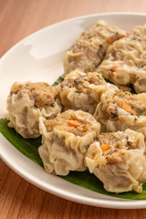 White Dish of Asian Steam  Dumplings  or Dim Sum a Famous Chinese Food  with Pork and Shrimp on  Wood Table.