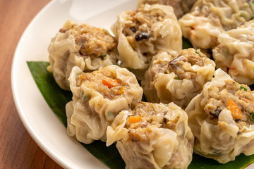 White Dish of Asian Steam  Dumplings  or Dim Sum a Famous Chinese Food  with Pork and Shrimp on  Wood Table.