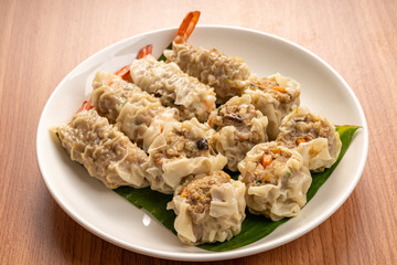 White Dish of Asian Steam  Dumplings  or Dim Sum a Famous Chinese Food  with Pork and Shrimp on  Wood Table.