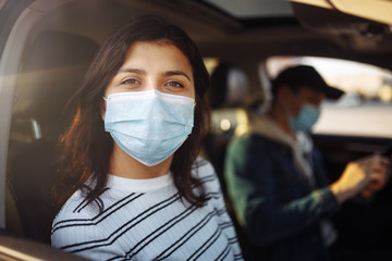 A girl and a boy driving in a car during coronavirus quarantine wearing medical masks. Safe taxi and healthcare during pandemic covid-19. Passangers virus safety concept,