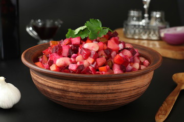 Traditional Russian salad vinaigrette with beans, pickles and boiled vegetables in a clay bowl against a black background, Vegetarian food, Horizontal format, Closeup