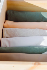 women's clothing in soft spring colors is neatly stacked in an open drawer of a wooden wardrobe