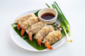 Close up Asian Steam  Dumplings  or Dim Sum a Famous Chinese Food  with Pork and Shrimp on Banana Leaf and White Dish with Garlic, Spring Onion and Peppers on White Isolated Background.