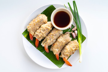 Close up Asian Steam  Dumplings  or Dim Sum a Famous Chinese Food  with Pork and Shrimp on Banana Leaf and White Dish with Garlic, Spring Onion and Peppers on White Isolated Background.