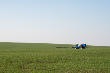 blue tractor sprinkles wheat, blue harvester sprinkles wheat, blue tractor sprinkles field from...