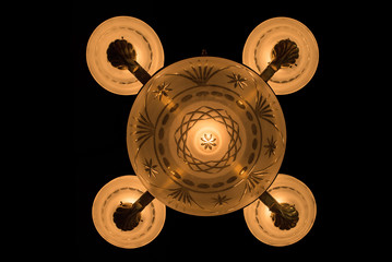 vintage chandelier on black background, bronze antique chandelier with burning light, bottom view of an antique bronze chandelier with glass shades, a vintage bronze chandelier with shades photo below