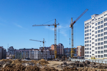 Extensive scaffolding providing platforms for work in progress on a new apartment block,Tall building under construction with scaffolds,Freestanding tower crane on a building site