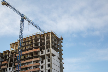 Extensive scaffolding providing platforms for work in progress on a new apartment block,Tall building under construction with scaffolds,Freestanding tower crane on a building site