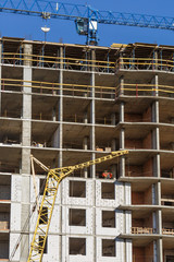 Extensive scaffolding providing platforms for work in progress on a new apartment block,Tall building under construction with scaffolds,Freestanding tower crane on a building site