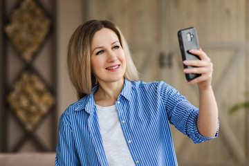 Woman blogger talking with followers, live streaming, looking to smartphone screen sitting on couch. Making video call to friends and parents. Social media, instagram, stay home and quarantine