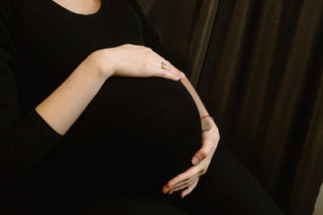 Motherhood, expectation of a beloved child. Mom strokes a large belly at the end of pregnancy. A woman feels tremors within herself.