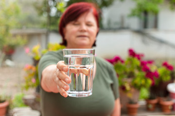 Mature woman is holding a glass of water in her hand. Health and healthy eating concept.