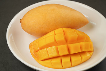 Fresh Mango on white plate and black pattern background
