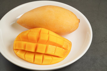 Fototapeta premium Fresh Mango on white plate and black pattern background
