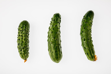 Three fresh cucumbers on a white background. The view from the top