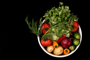 Vegetables in a bowl on a black background with copy space. The view from the top